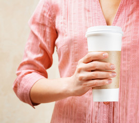 Young woman holding a tumbler of coffee in cafe