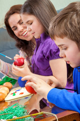 Mother and her children paint easter eggs