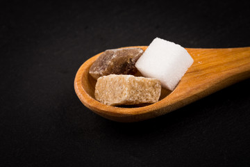 White refined and brown sugar in wooden spoon
