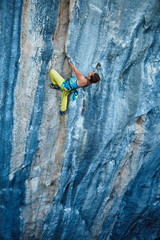 Fototapeta premium Rock climber climbing up a cliff