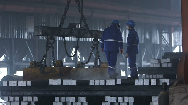Workers transfer steel blocks