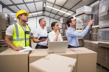 Warehouse manager pointing something to his colleagues