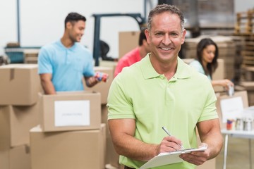 Fototapeta premium Smiling volunteer man taking notes holding clipboard