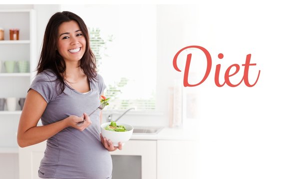 Attractive pregnant woman holding a bowl of salad w