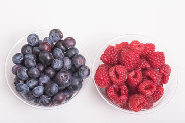 Blueberries and Raspberries in Cups on White