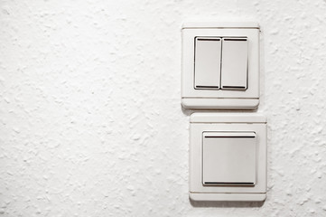 White plastic light switchers on white wallpapered wall
