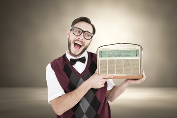 Composite image of geeky hipster holding a retro radio