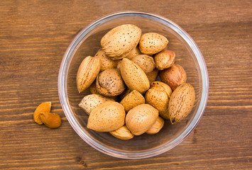 Almonds on bowl on wooden table top views