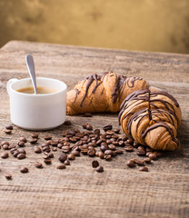 Breakfast with coffee, milk and croissants on wooden table