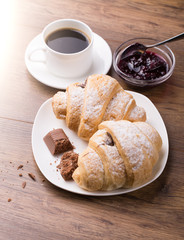 Breakfast with coffee, jam and croissants on wooden table