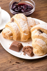 Breakfast with coffee, milk and croissants on wooden table