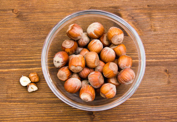 Hazelnuts on bowl on wooden table top views