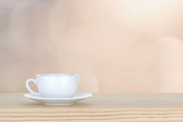 white cup of coffee on pine Wooden Table and bokeh,defocused lig