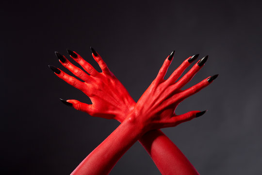 Crossed red devil hands with black nails