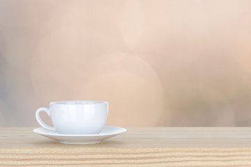 Fototapeta na wymiar white cup of coffee on pine Wooden Table and bokeh,defocused lig