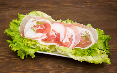 Rolled bacon on salad on wooden table