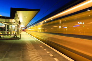 Train leaving a train station in the evening.