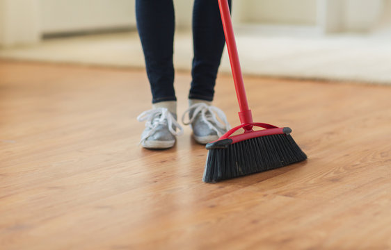 close up of woman legs with broom sweeping floor