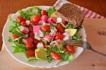 Mixed vegetable salad with crab sticks and avocado