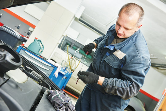 mechanic checking oil level in automobile