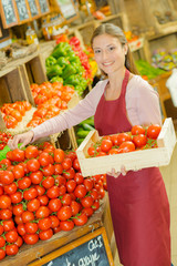 Shop worker carrying a crate of tomatoes