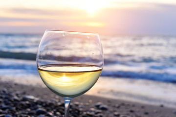 glass of wine sitting on the beach at colorful sunset - 79744512