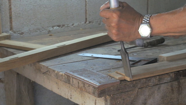 craftsman woodcarver carving wood object with chisel tool