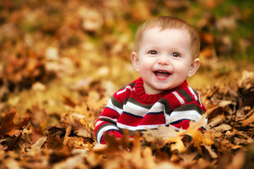 Happy child playing in a leaf pile during fall or winter