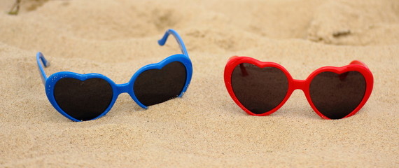 Colorful sunglasses shaped heart on the sand