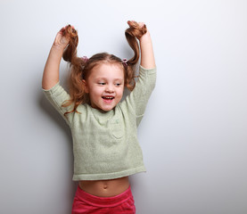 Happy playful kid girl in blouse holding hair with empty space