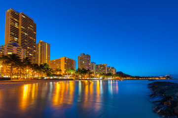 Obraz premium Tall buildings on Waikiki reflect in the water