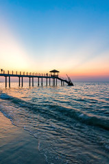 Colorful sunset at tropical beach with jetty