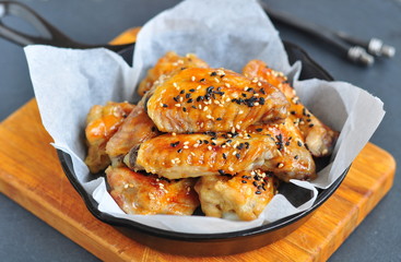 Chicken wings in a sweet and sour sauce with sesame on the pan