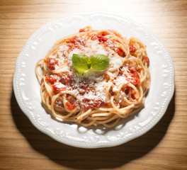 dish with spaghetti and tomato sauce on the wooden table