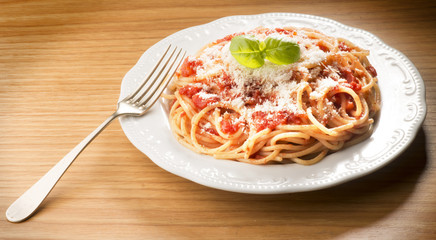 dish with spaghetti and tomato sauce on the wooden table