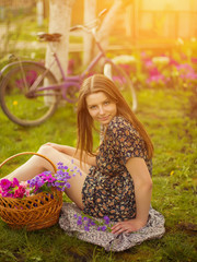 Beautiful young woman in dress sitting on grass near old vintage