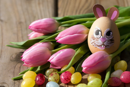 Osterei mit Hasengesicht und Tulpen
