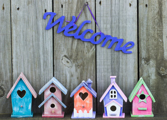 Welcome sign hanging over colorful birdhouses