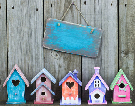 Blank blue sign hanging over colorful birdhouses