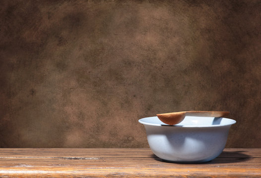 Blue bowl and wooden spoon on brown grunge background