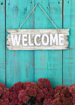 Welcome sign hanging on fence with flower border