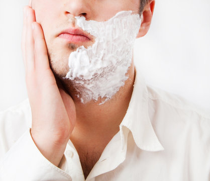 Young Man With Foam Shaving His Beard Off With An Electric Shave