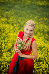 Naklejka na ściany i meble Beautiful young blonde woman in red dress with camomile flowers