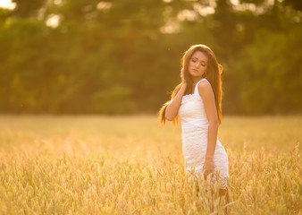 Fototapeta na wymiar beautiful woman posing in yellow wheat field