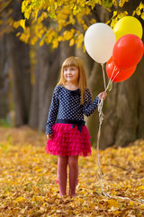 little girl plays with balloons in autumn park