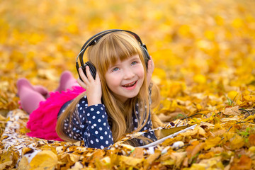 Fototapeta premium Young fashion girl with headphones an tablet pc lying at yellow