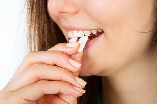 Young charming smiling woman puts in mouth chewing gum, close up
