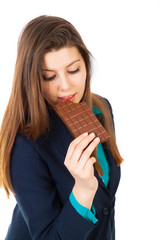 pretty businesswoman eating a bar of chocolate against a white b