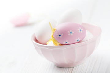 Easter egg in the pink bowl full of white eggs