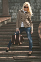 Stylish beautiful blonde girl staying on a stairs. Brown color t